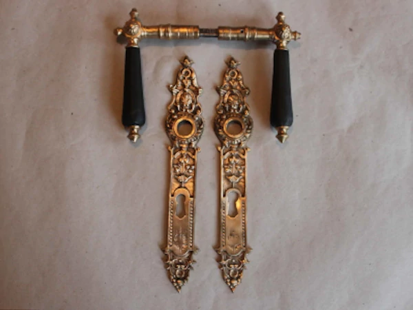 Antike Gründerzeit Türdrückergarnitur aus Messing mit reich ornamentierten Langschildern, floralen Kartuschen und dunklen Holzgriffen