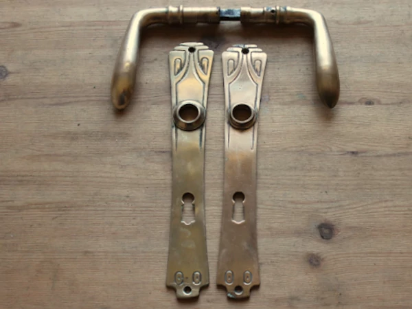 Jugendstil Türklinke aus Messing mit geschwungenen Pflanzenornamenten und schlankem Langschild