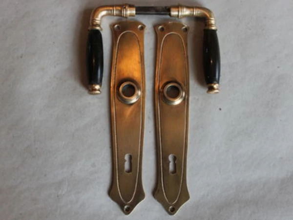 Schlichte Jugendstil Türklinke aus Messing mit ovalem Linienfeld auf Langschild und schwarzem Griffeinsatz